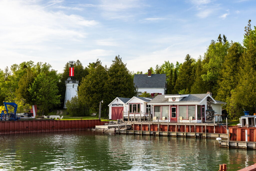 Waterfront view of South Pipe Island featuring the historic 1887 lighthouse, private harbor, and waterfront residences in northern Lake Huron.