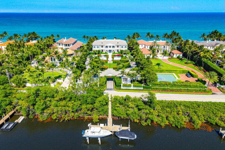 Aerial view of a Manalapan ocean-to-Intracoastal estate with lush landscaping, waterfront dock and direct ocean frontage.