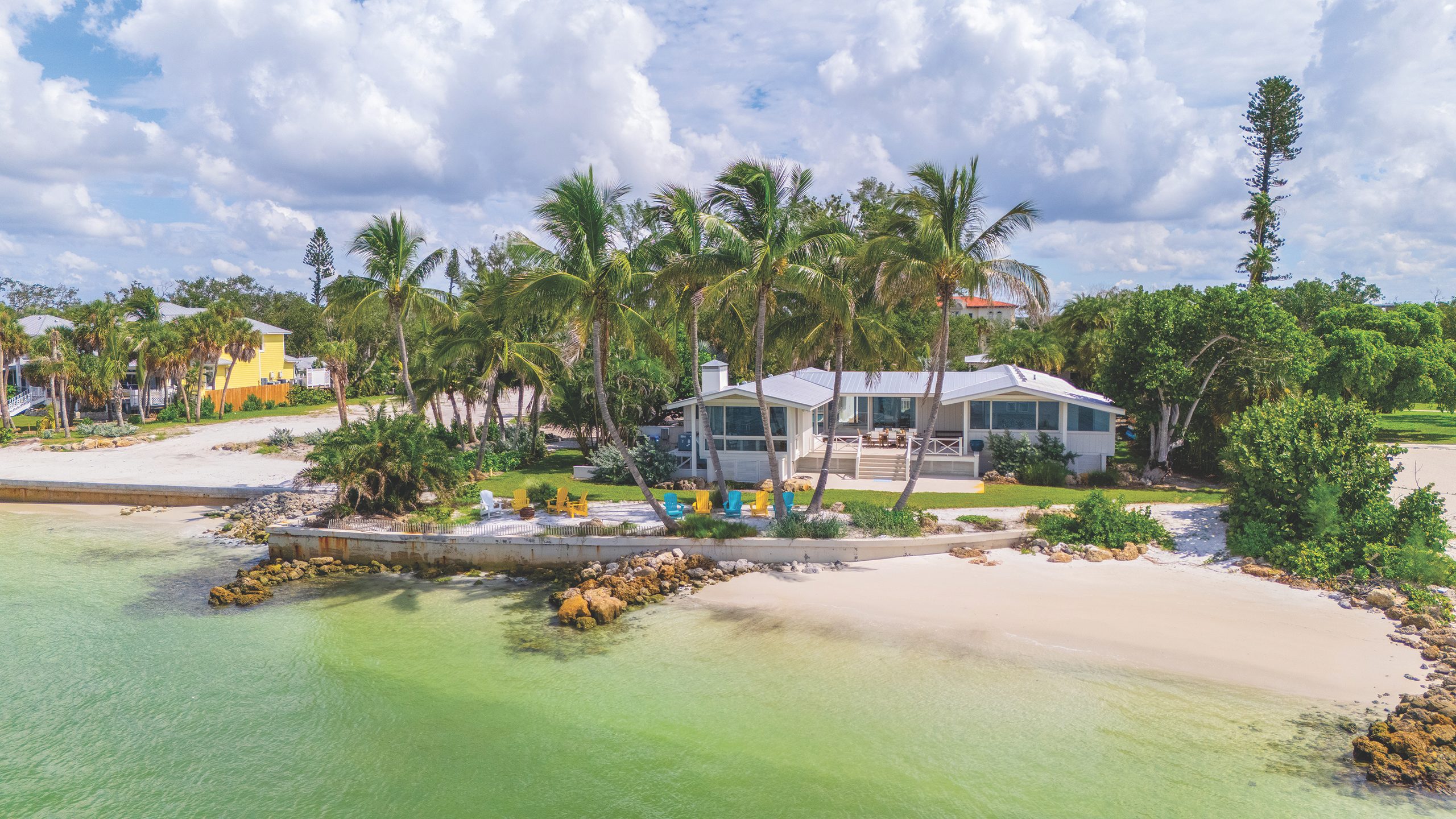 Waterfront residence at The Higel Estate on Siesta Key, featuring a private sandy beach, tropical palm trees, and turquoise Gulf Coast waters.